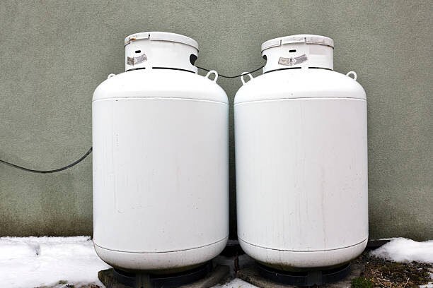 Two white propane tanks against green wall. Horizontal.-For more propane, click here. PROPANE